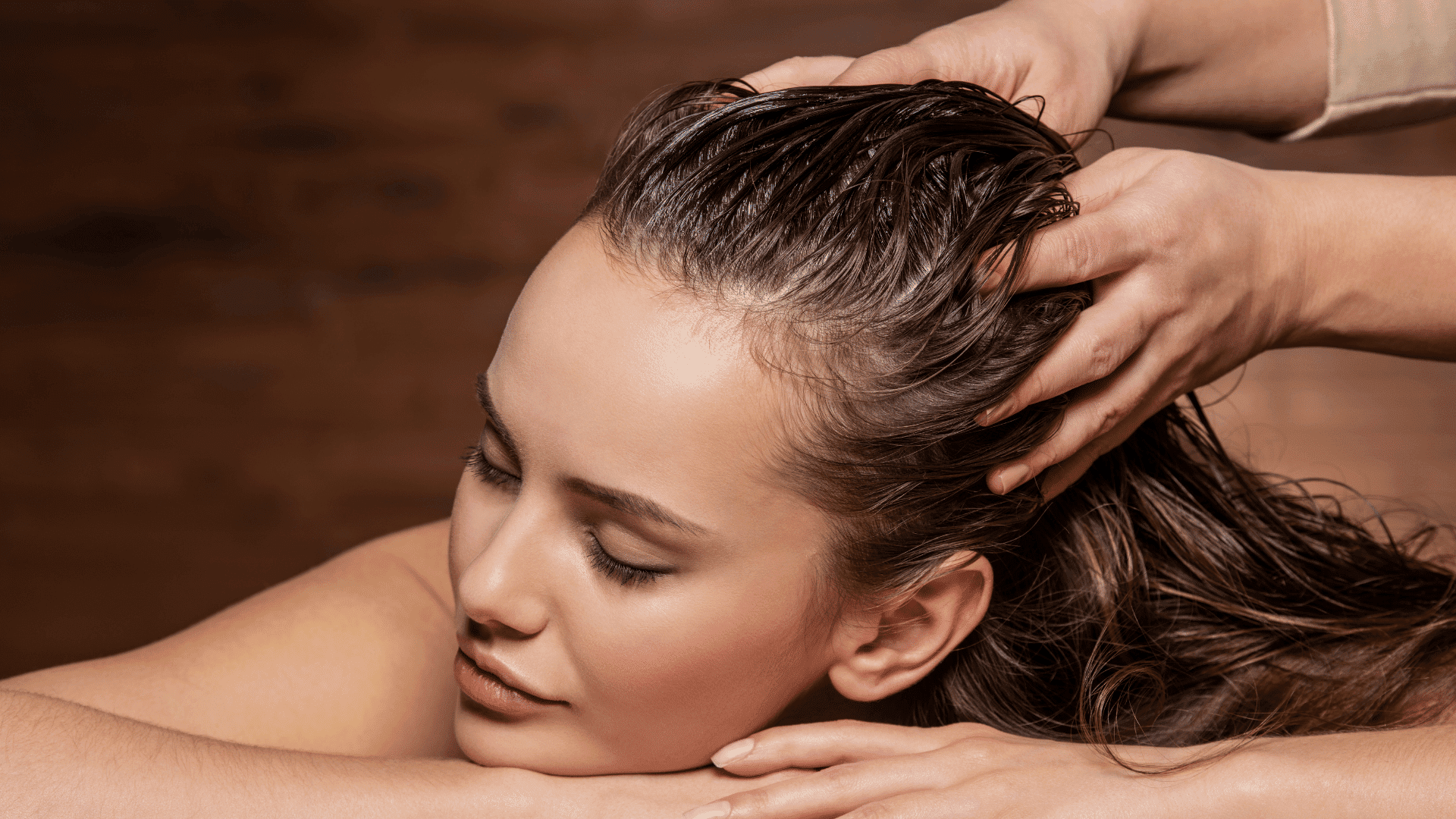 Head massage therapy with hands applying gentle pressure on woman's scalp.