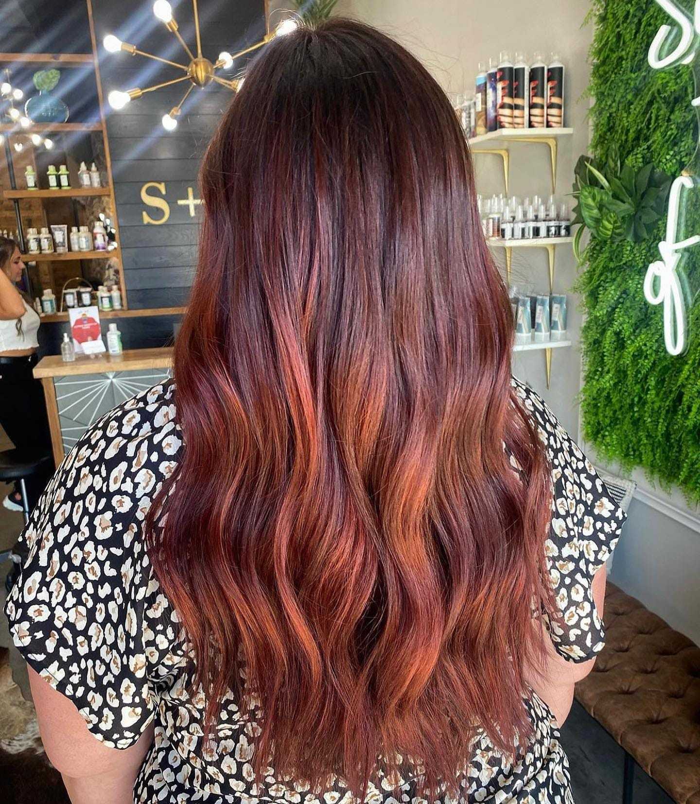 Long, wavy brunette hair with highlights, styled in a salon with elegant decor.