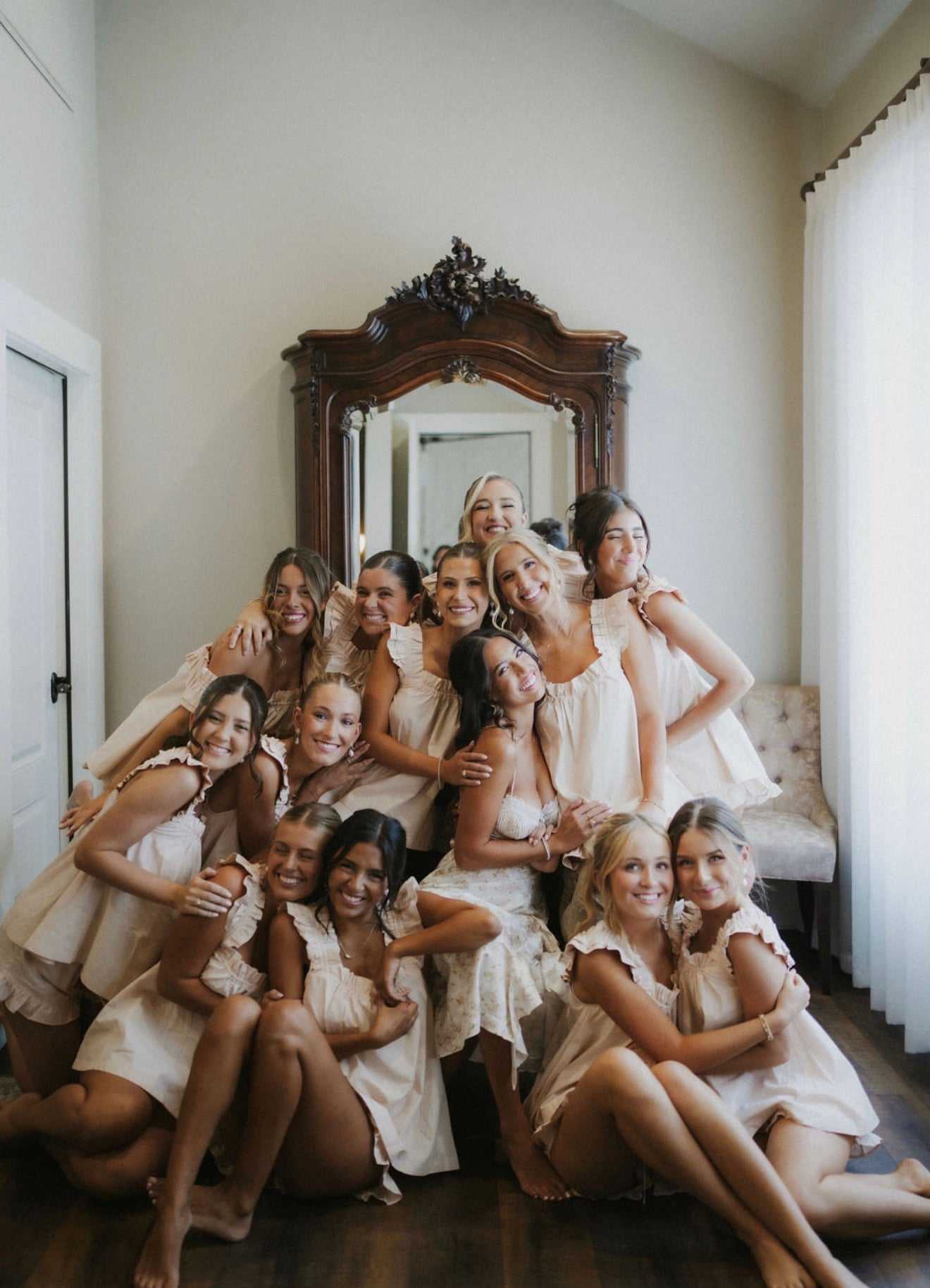 Group of smiling women in matching dresses posing indoors.