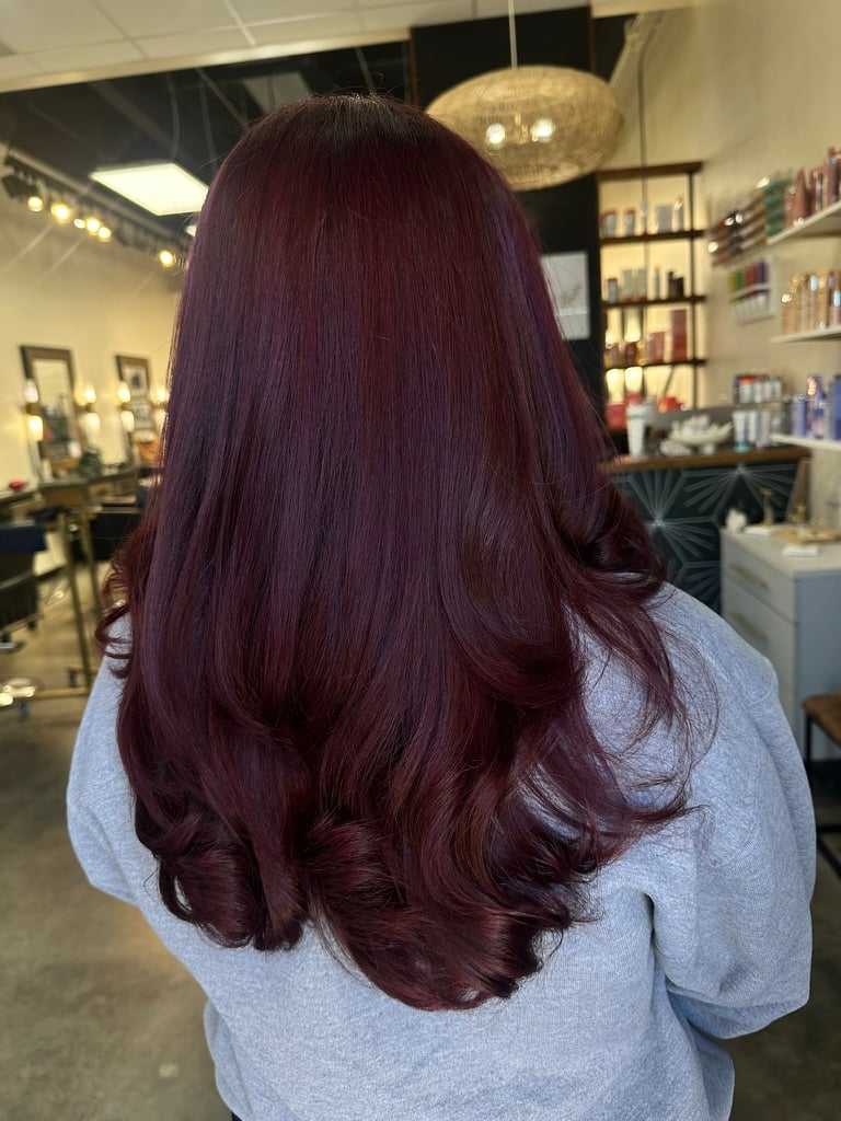 Woman with long, wavy, auburn hair in a salon setting.