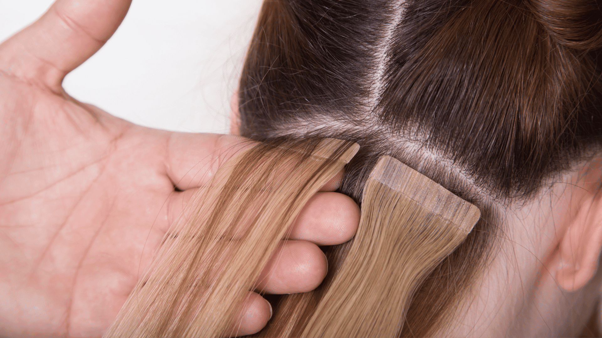 Hair extensions being applied to a woman's scalp, showing blending with natural hair.